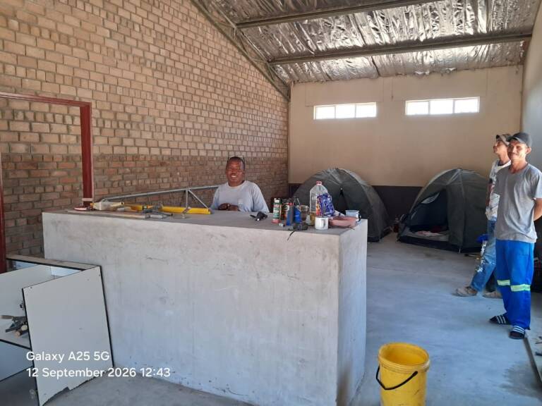 Ds. Jafet staan gereed agter die toonbank van die Omatako winkel, saam met ons twee bouers - Ricky en Wayne.